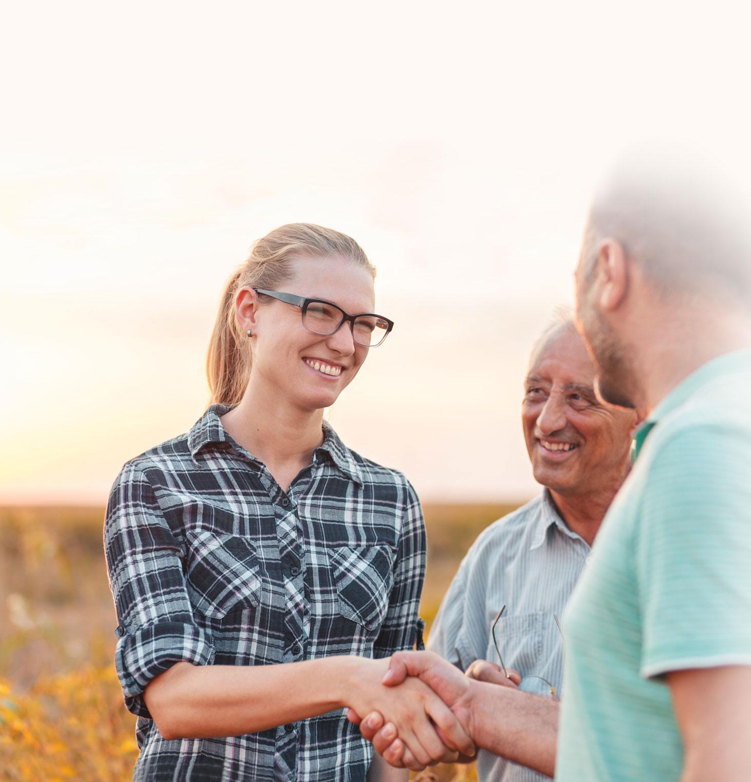 People shaking hands in a corn field