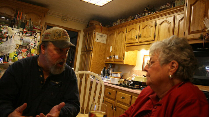 Couple talking in a kitchen.