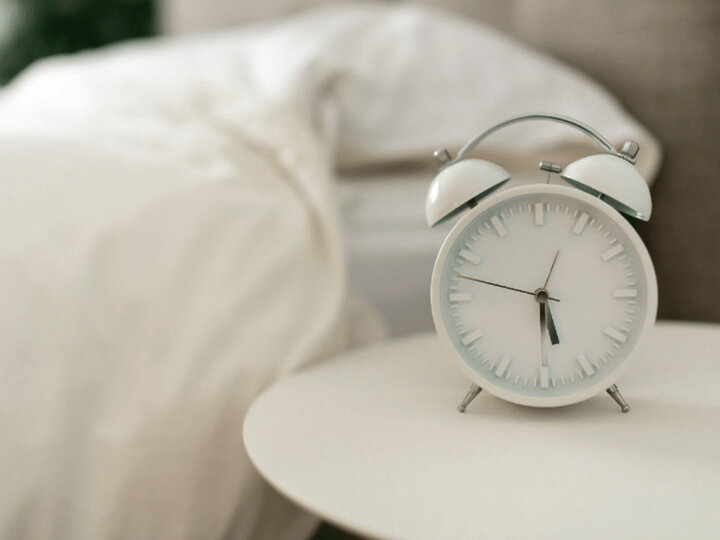 Alarm clock next to a bed.